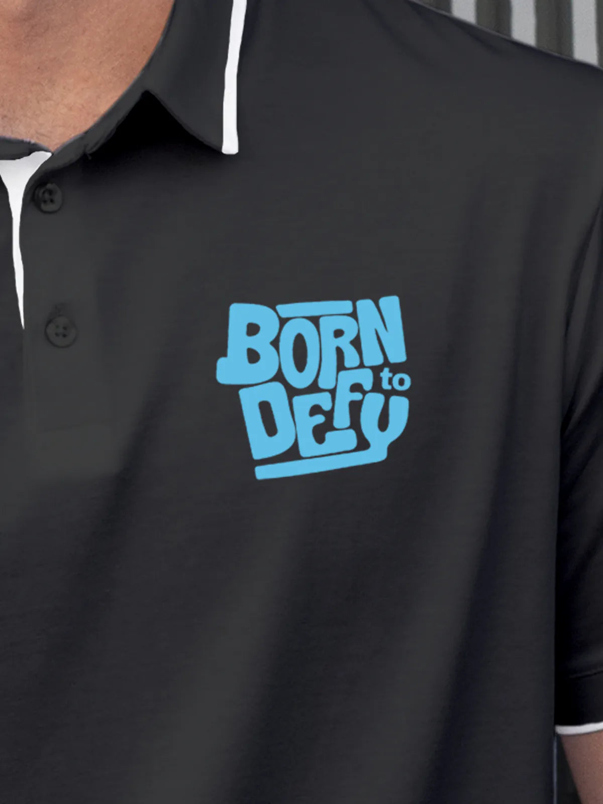 Close up of 'Born To Defy' on Men's Dark Grey Polo T-shirt, highlighting intricate details and vibrant print.