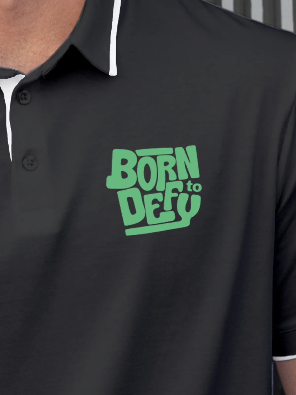 Close up of 'Born To Defy' on Men's Dark Grey Polo T-shirt, highlighting intricate details and vibrant print.