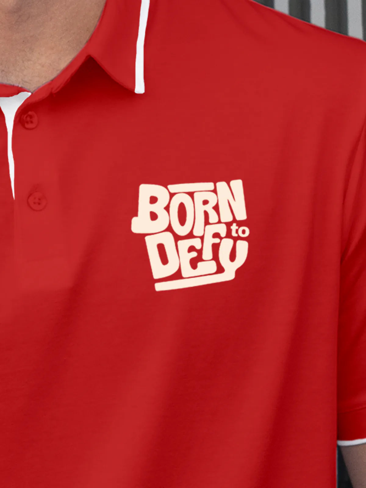 Close up of 'Born To Defy' on Men's Red Polo T-shirt, highlighting intricate details and vibrant print.