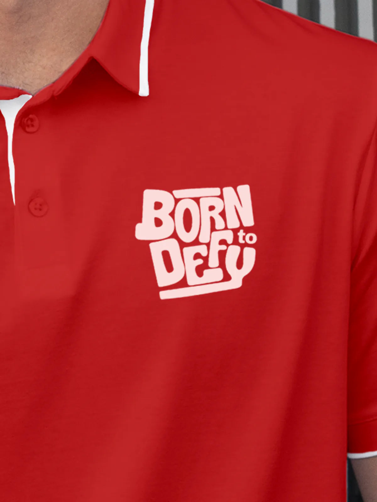 Close up of 'Born To Defy' on Men's Red Polo T-shirt, highlighting intricate details and vibrant print.