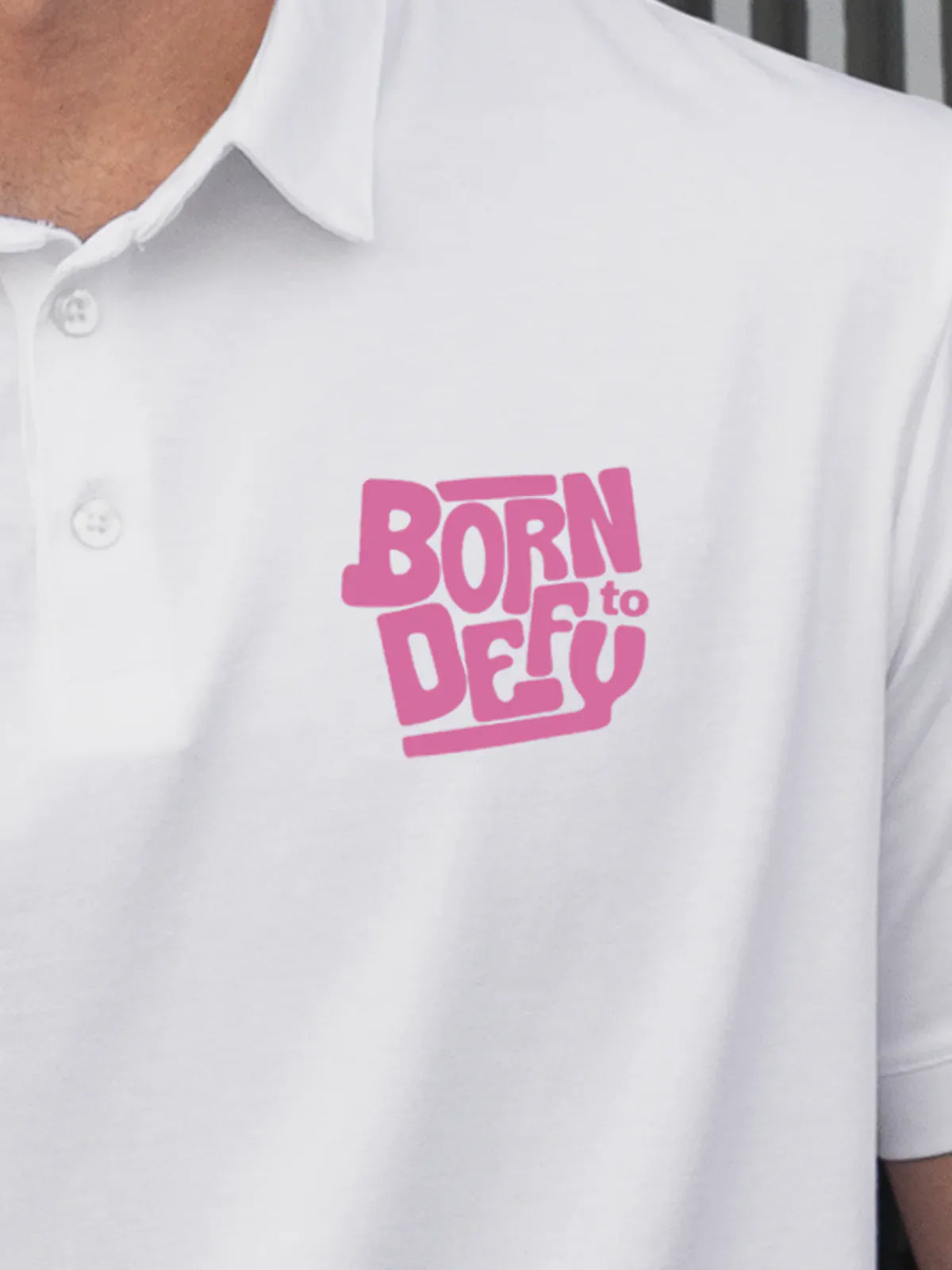 Close up of 'Born To Defy' on Men's White Polo T-shirt, highlighting intricate details and vibrant print.