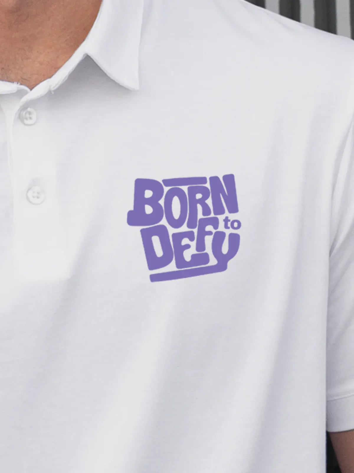 Close up of 'Born To Defy' on Men's White Polo T-shirt, highlighting intricate details and vibrant print.