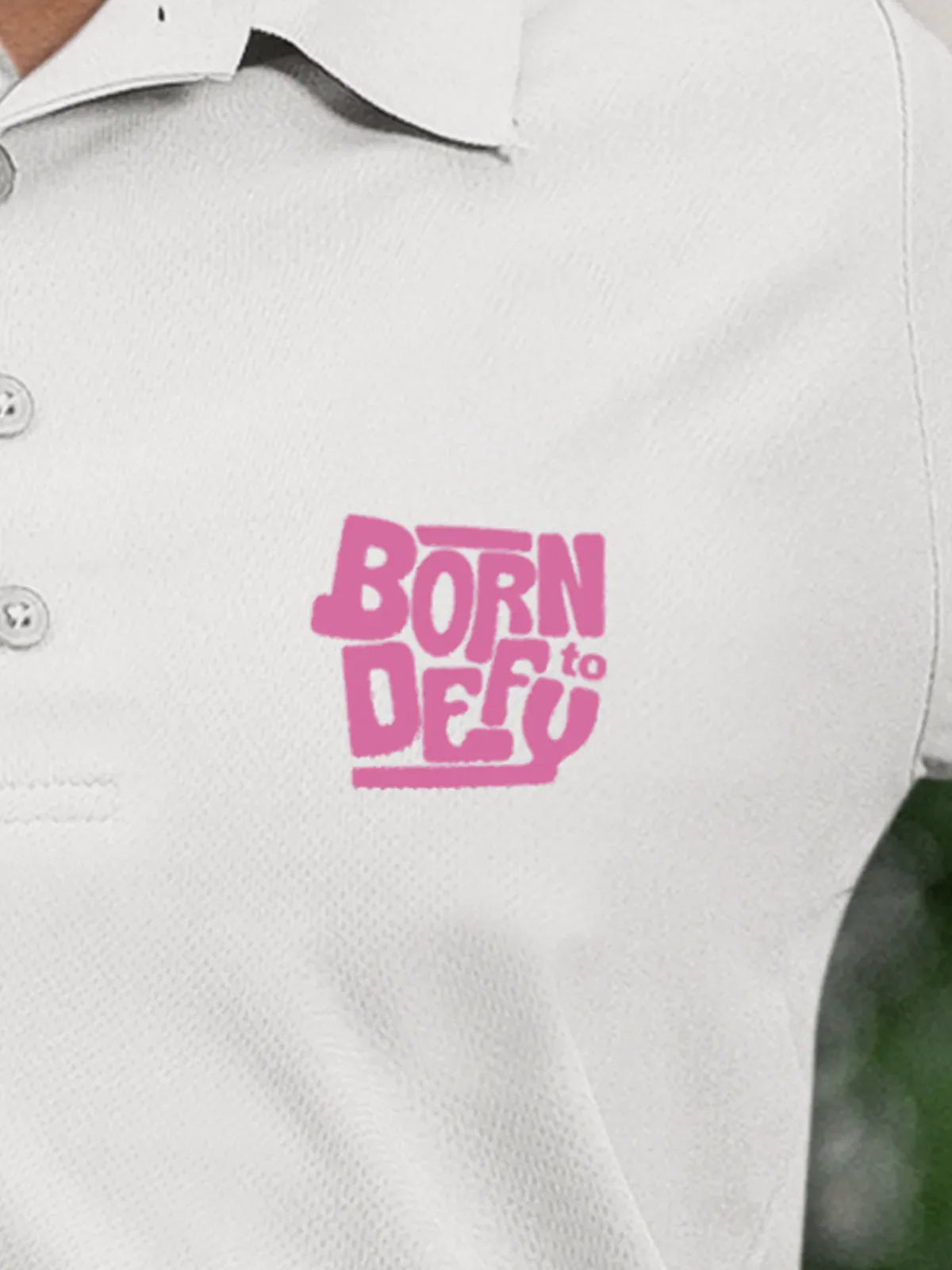 Close up of 'Born To Defy' on Women's White Polo T-shirt, highlighting intricate details and vibrant print.