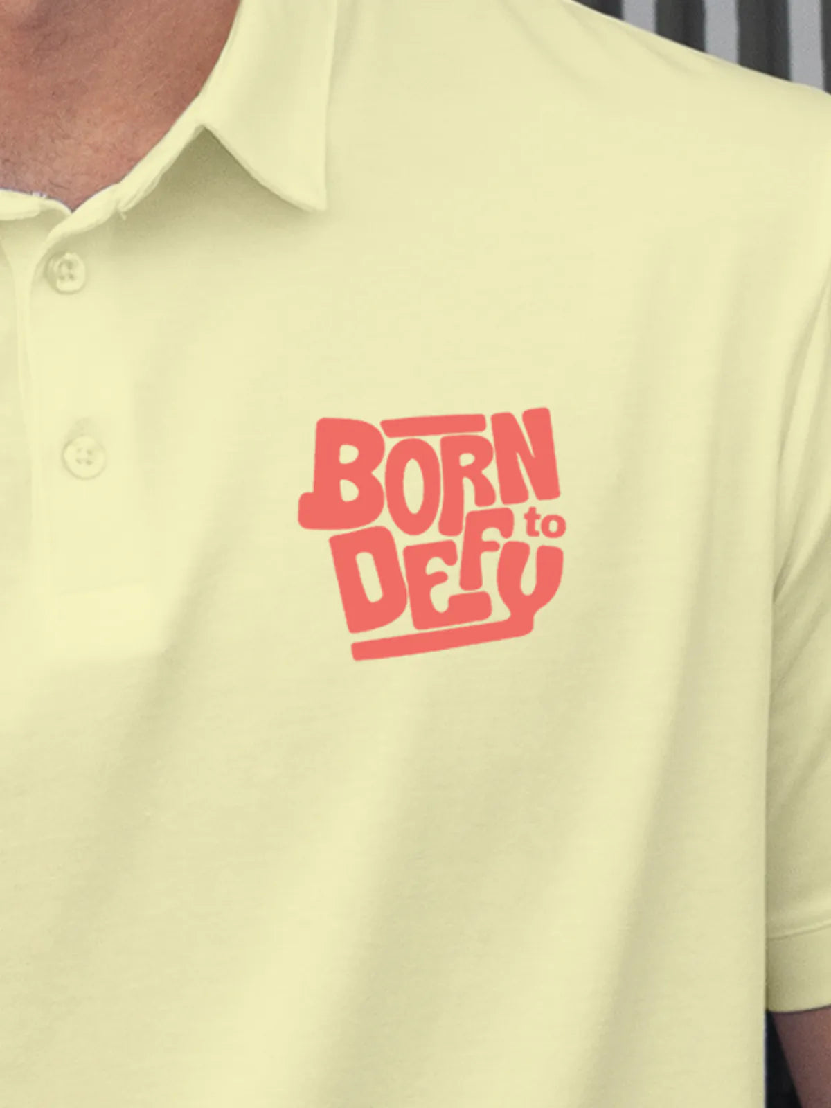 Close up of 'Born To Defy' on Men's Yellow Polo T-shirt, highlighting intricate details and vibrant print.