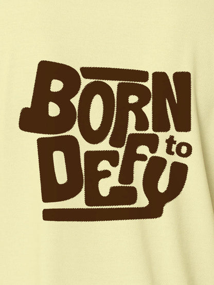 Close up of 'Born To Defy' design on Women's Yellow Polo T-shirt, highlighting intricate details and vibrant print.