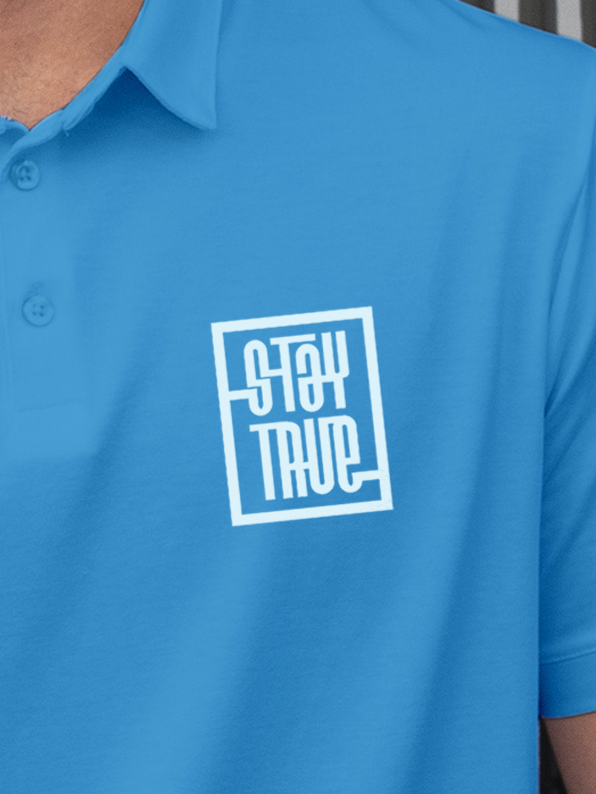 Close up of 'Stay True' on Men's Blue Polo T-shirt, highlighting intricate details and vibrant print.