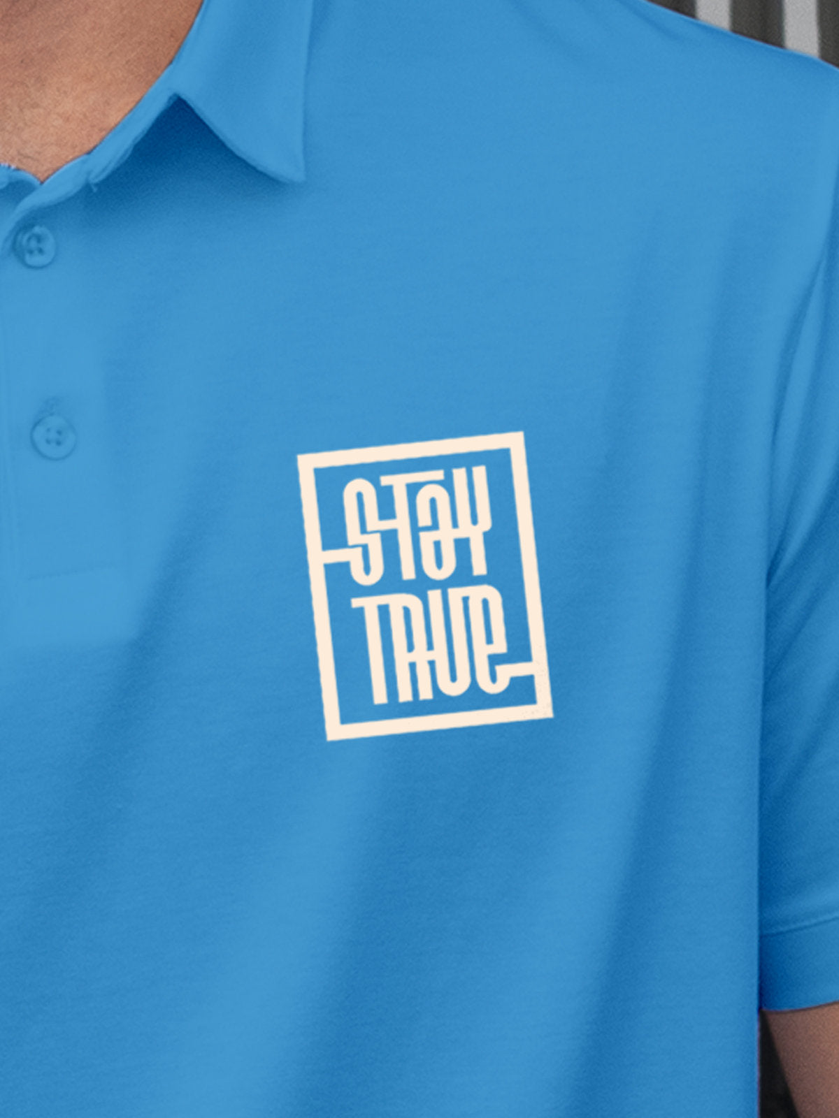 Close up of 'Stay True' on Men's Blue Polo T-shirt, highlighting intricate details and vibrant print.