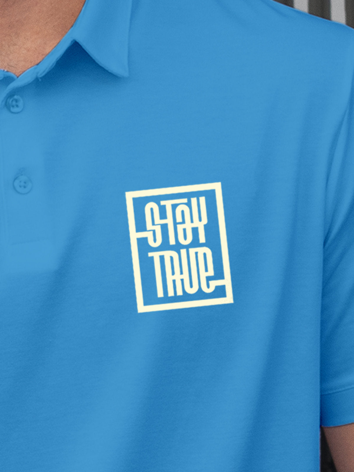 Close up of 'Stay True' on Men's Blue Polo T-shirt, highlighting intricate details and vibrant print.