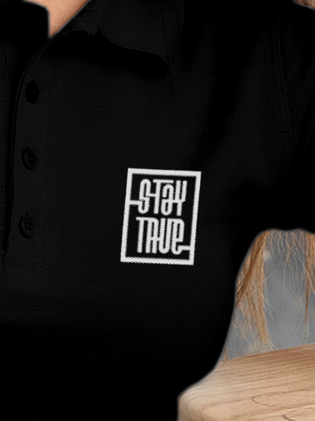 Close up of 'Stay True' design on Women's Black Polo T-shirt, highlighting intricate details and vibrant print.
