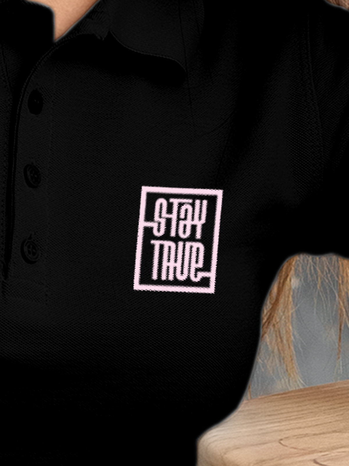 Close up of 'Stay True' on Women's Black Polo T-shirt, highlighting intricate details and vibrant print.