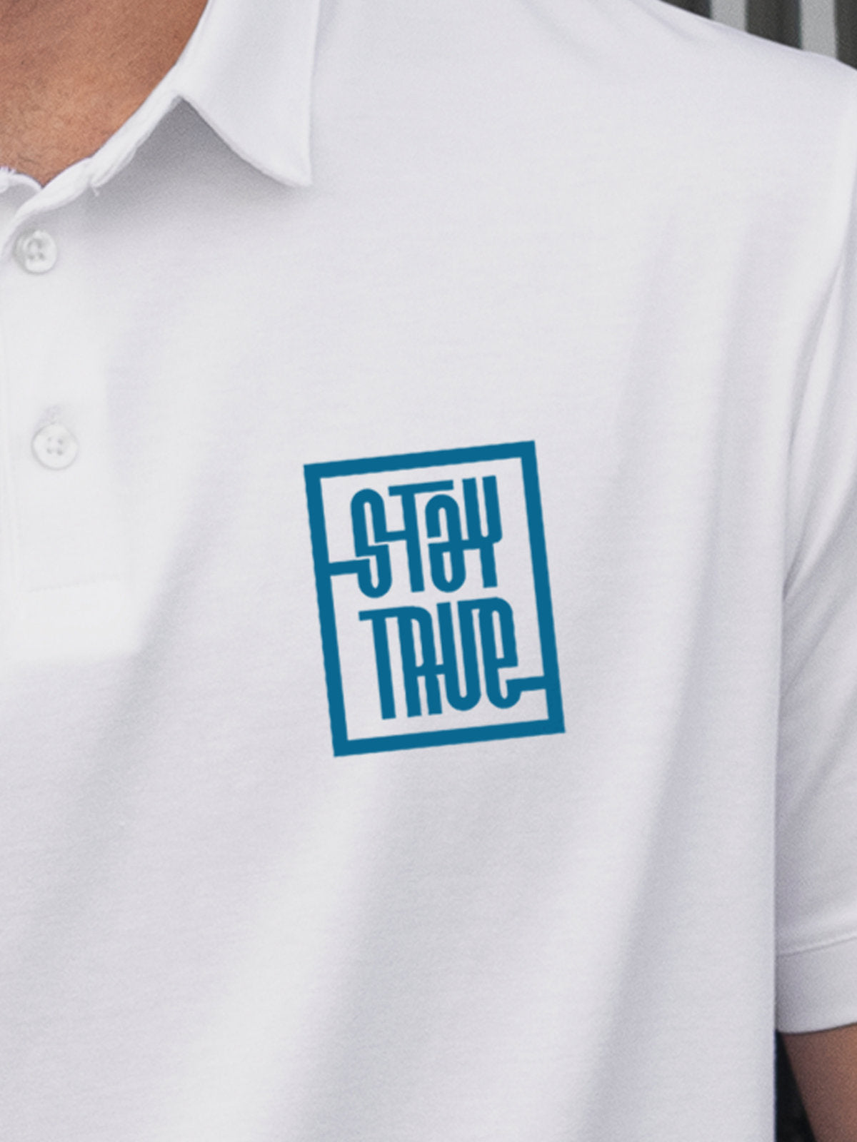Close up of 'Stay True' on Men's White Polo T-shirt, highlighting intricate details and vibrant print.