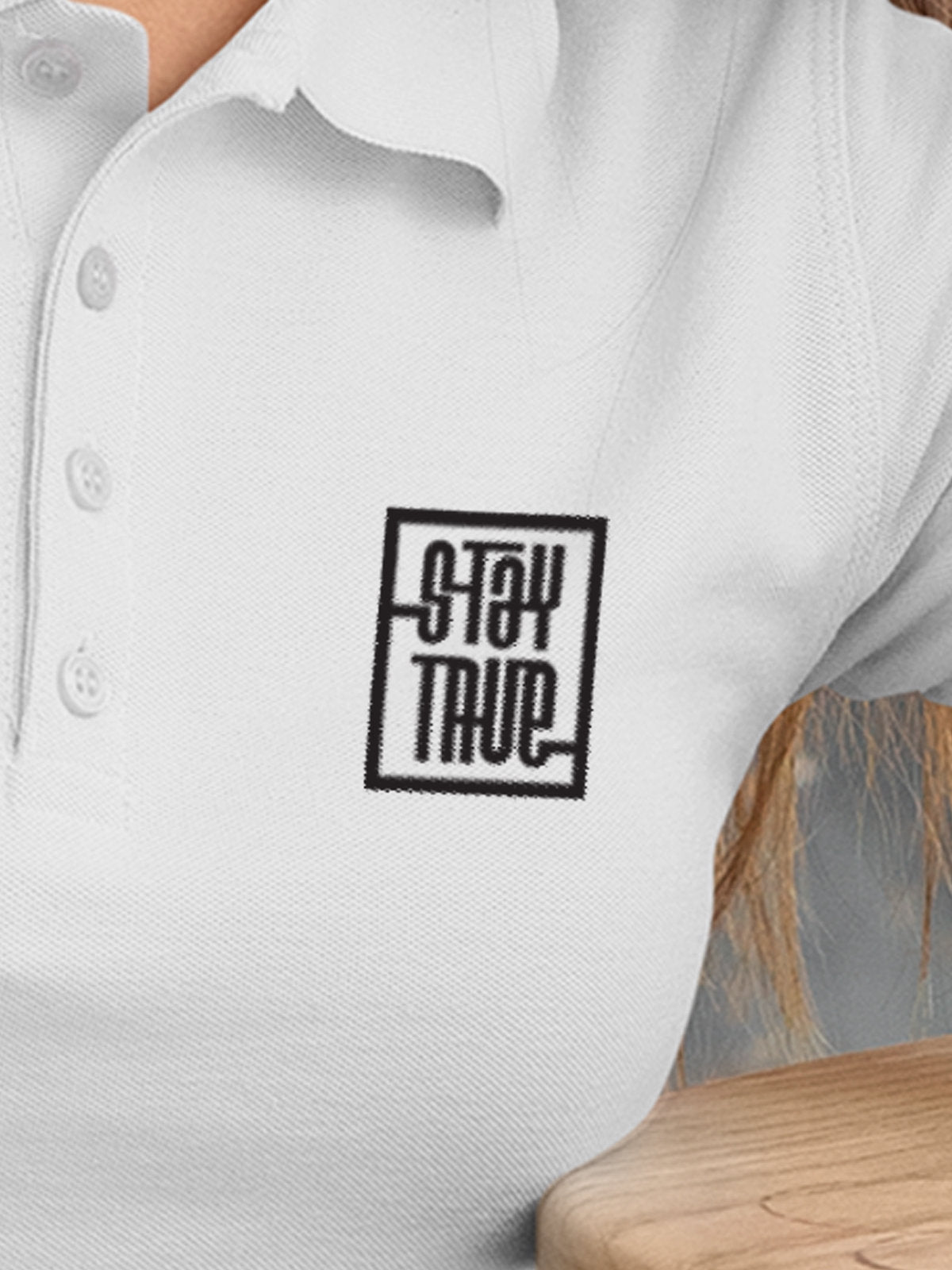Close up of 'Stay True' on Women's White Polo T-shirt, highlighting intricate details and vibrant print.