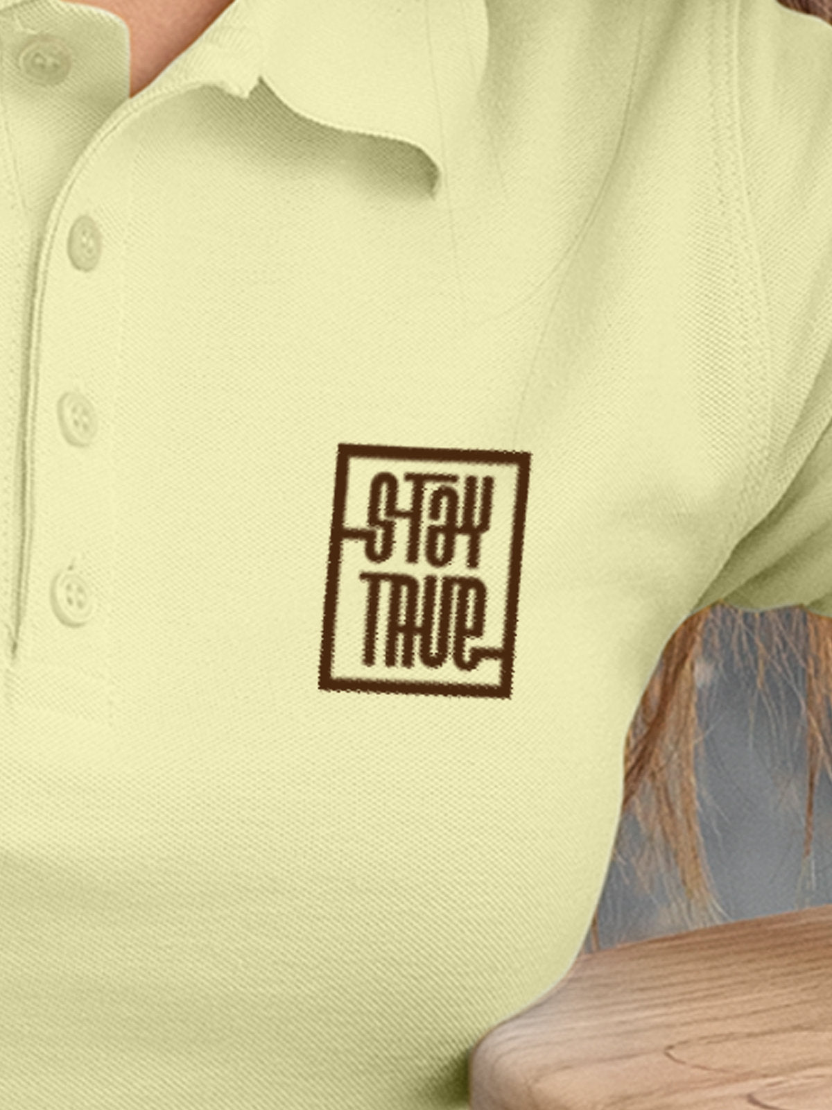 Close up of 'Stay True' on Women's Yellow Polo T-shirt, highlighting intricate details and vibrant print.