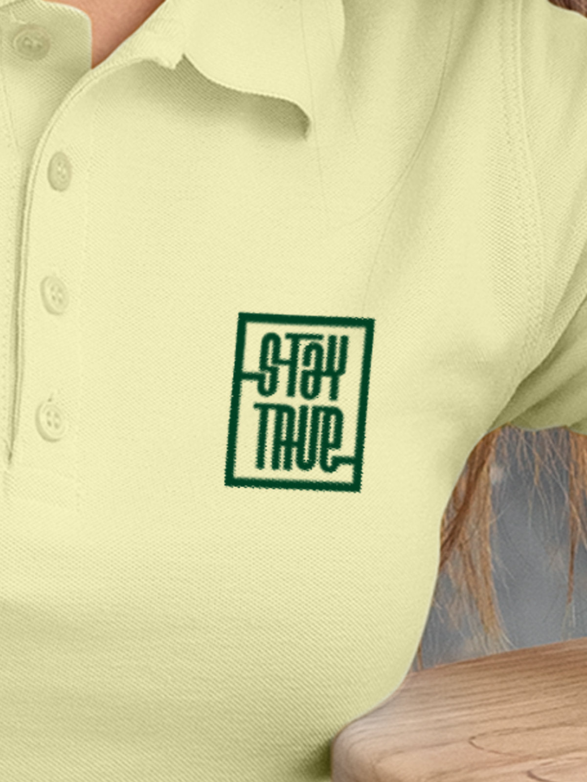 Close up of 'Stay True' on Women's Yellow Polo T-shirt, highlighting intricate details and vibrant print.