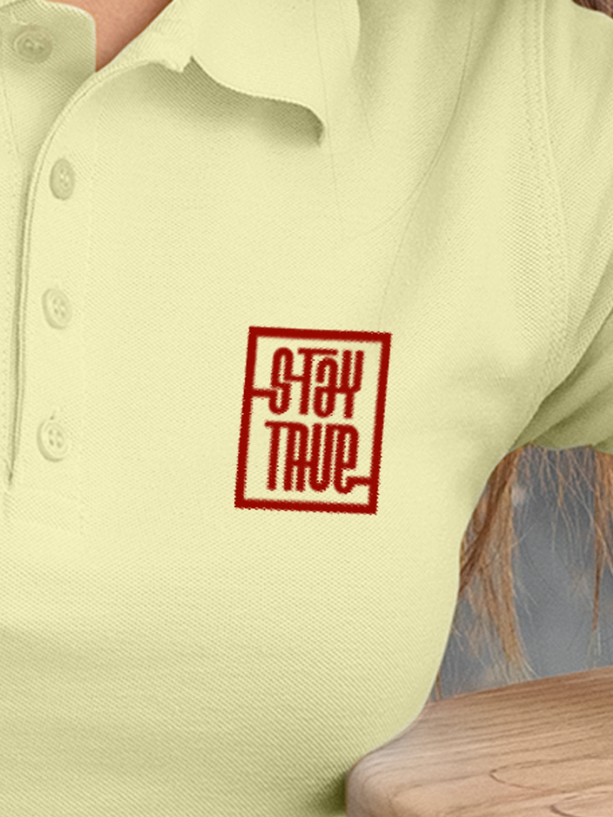Close up of 'Stay True' on Women's Yellow Polo T-shirt, highlighting intricate details and vibrant print.