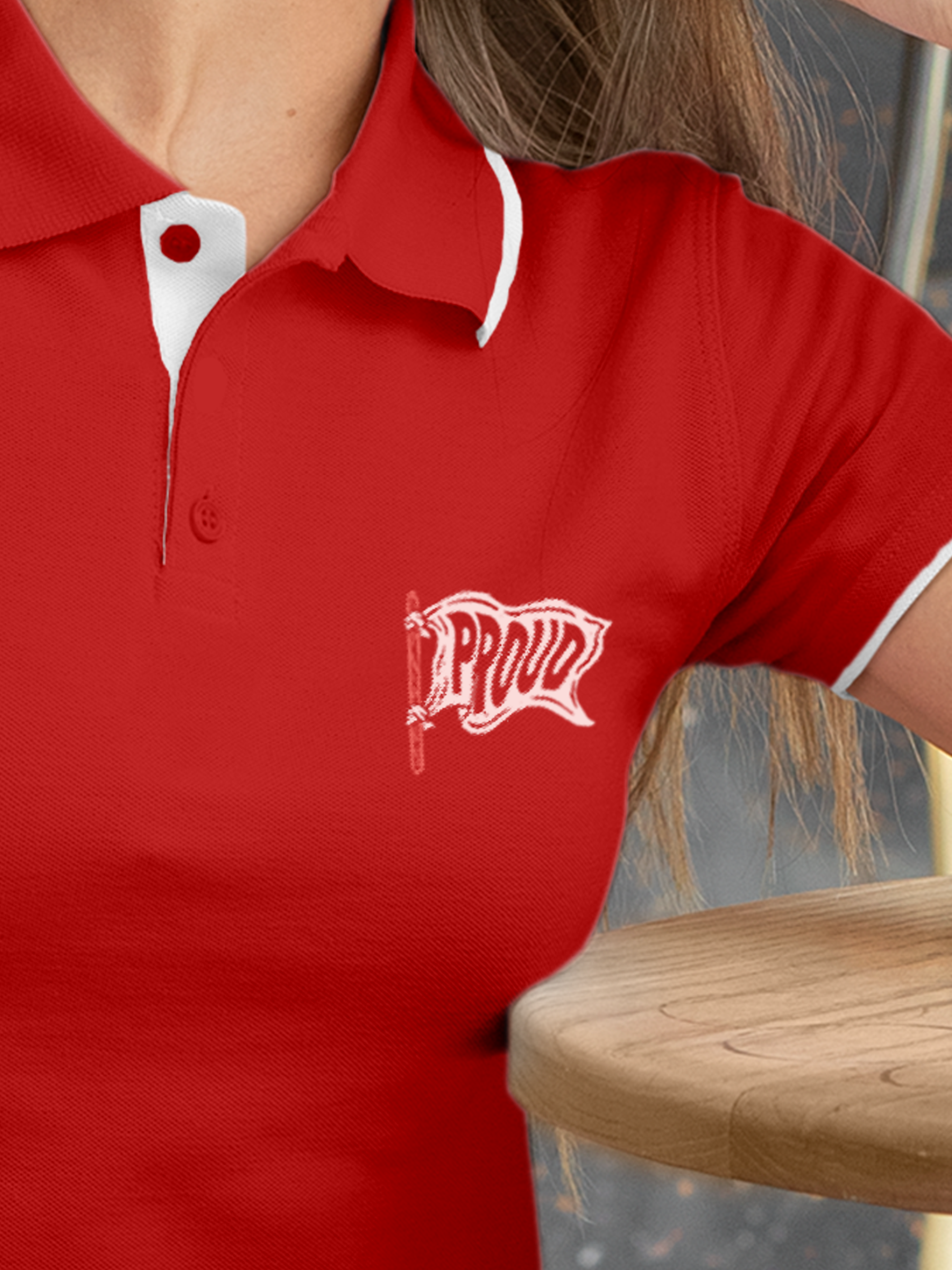 Close up of 'Proud' design on Women's Red Polo T-shirt, highlighting intricate details and vibrant print.