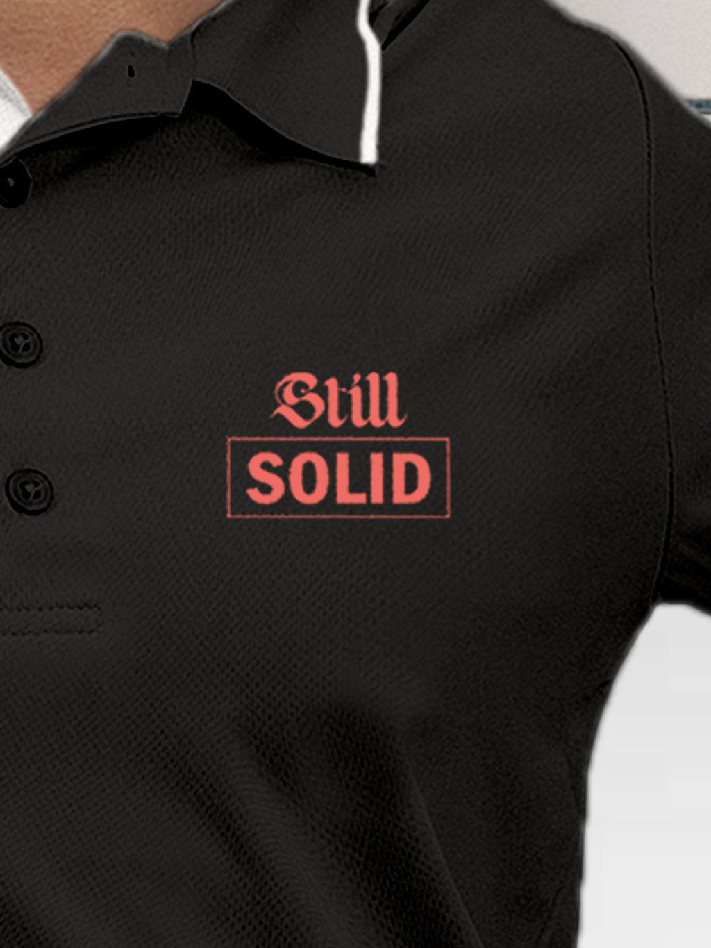 Close up of 'Still Solid' design on Women's Dark Grey Polo T-shirt, highlighting intricate details and vibrant print.