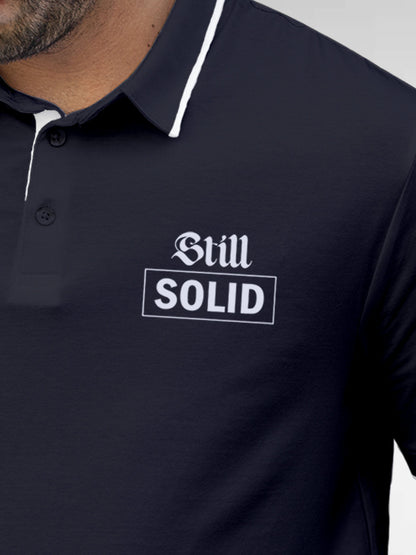 Close up of 'Still Solid' design on Men's Navy Blue Polo T-shirt, highlighting intricate details and vibrant print.