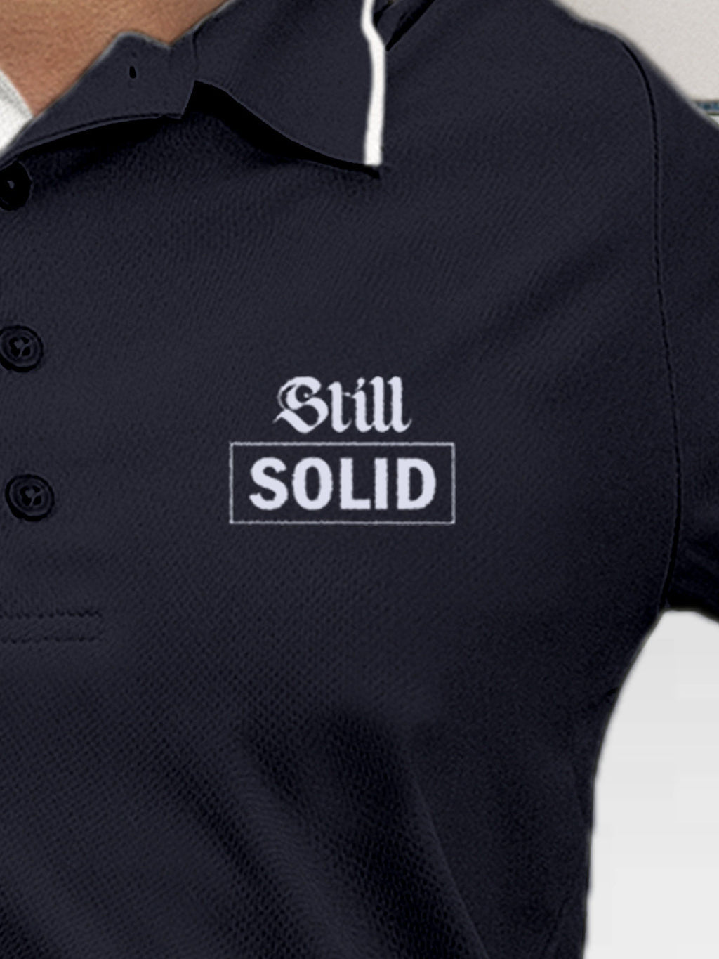 Close up of 'Still Solid' design on Women's Navy Blue Polo T-shirt, highlighting intricate details and vibrant print.