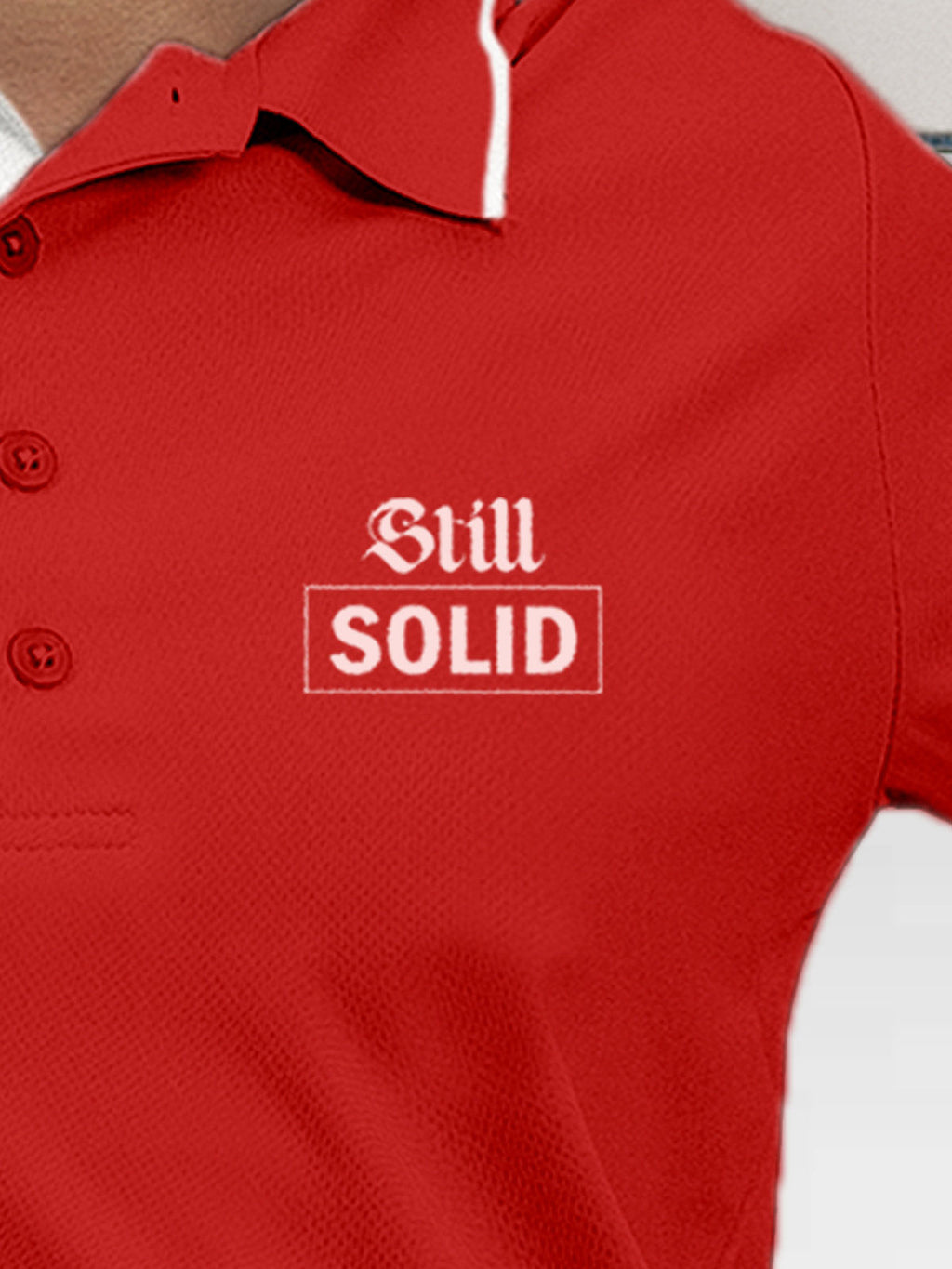 Close up of 'Still Solid' design on Women's Red Polo T-shirt, highlighting intricate details and vibrant print.