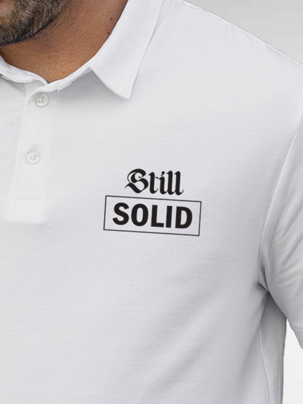 Close up of 'Still Solid' design on Men's White Polo T-shirt, highlighting intricate details and vibrant print.
