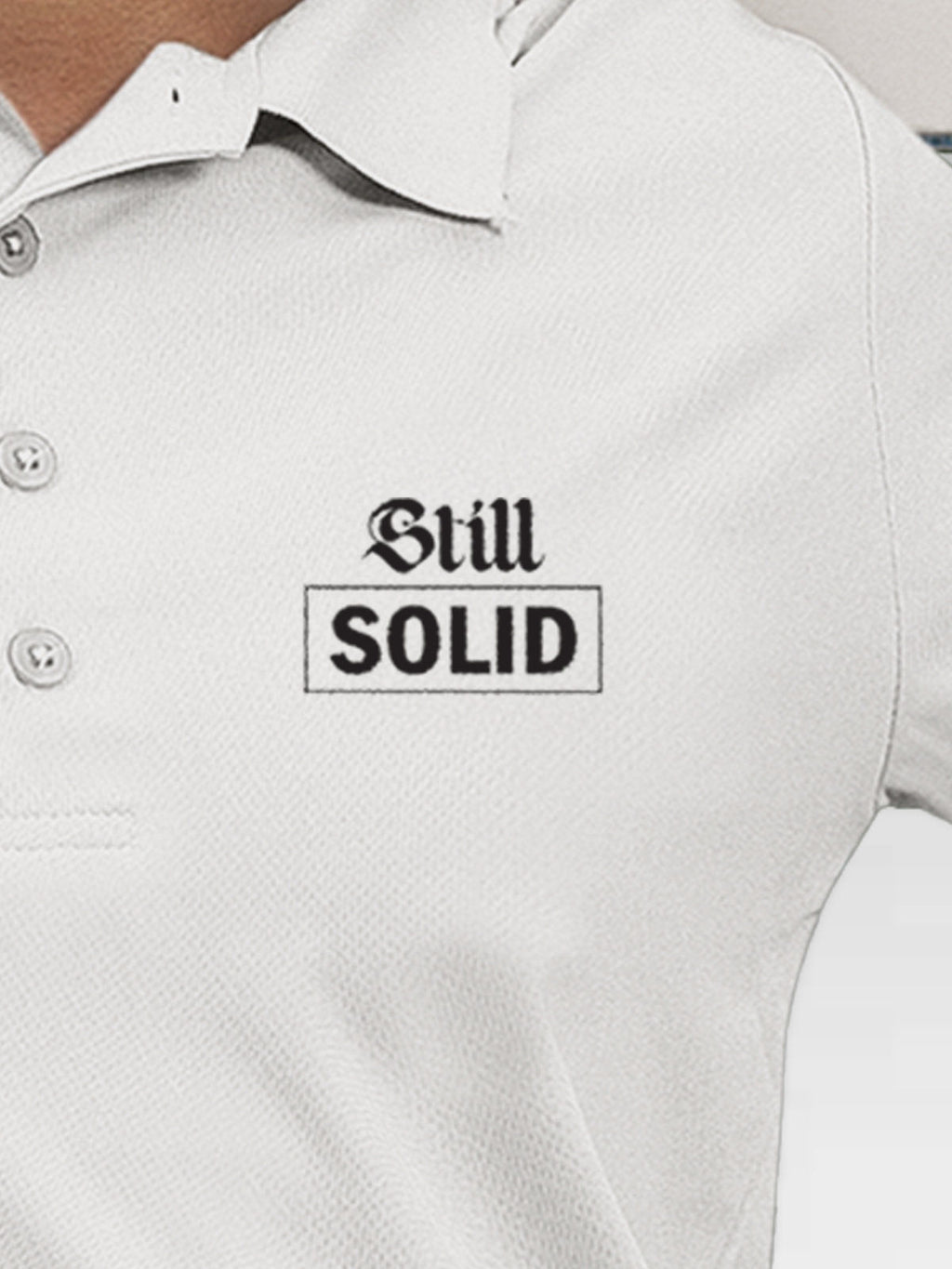 Close up of 'Still Solid' design on Women's White Polo T-shirt, highlighting intricate details and vibrant print.