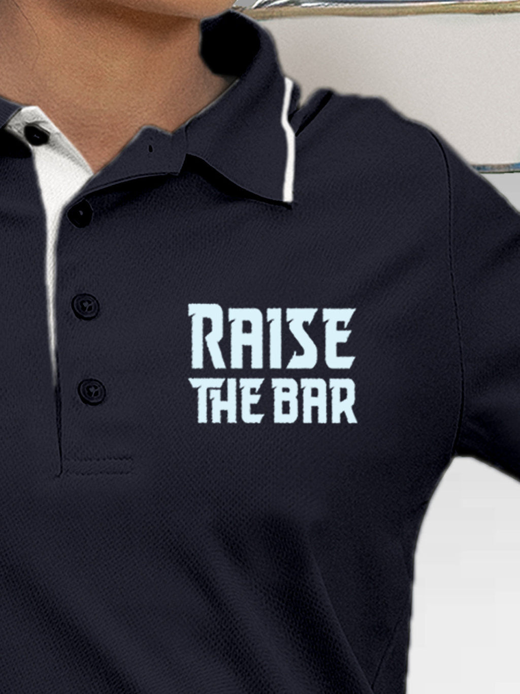 Close up of 'Raise The Bar' design on Women's Navy Blue Polo T-shirt, highlighting intricate details and vibrant print.