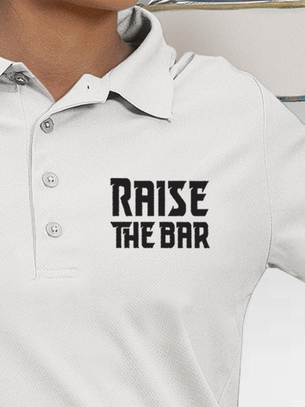 Close up of 'Raise The Bar' design on Women's White Polo T-shirt, highlighting intricate details and vibrant print.