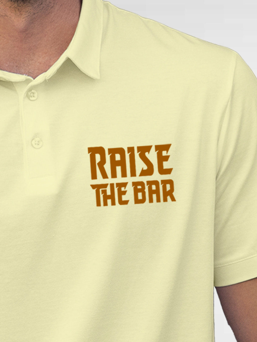 Close up of 'Raise The Bar' design on Men's Yellow Polo T-shirt, highlighting intricate details and vibrant print.