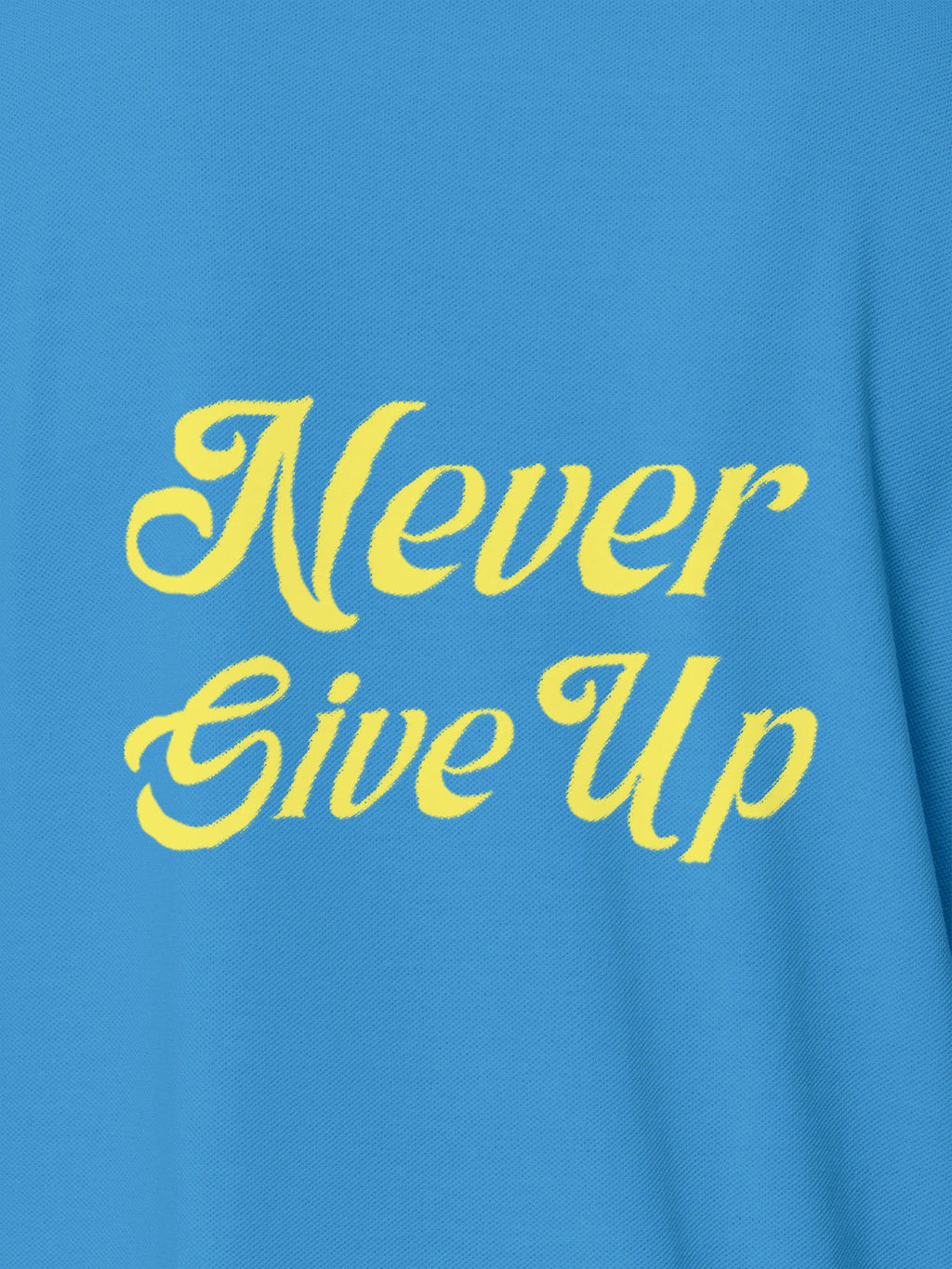 Close up of 'Never Give Up' design on Women's Blue Polo T-shirt, highlighting intricate details and vibrant print.