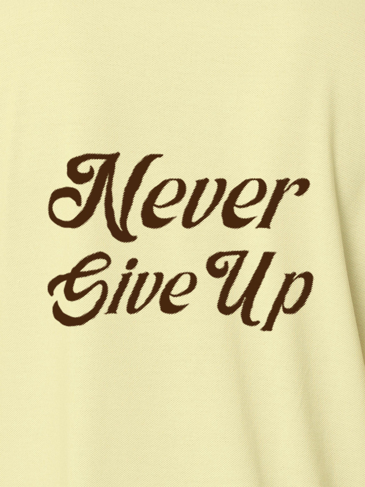 Close up of 'Never Give Up' design on Women's Yellow Polo T-shirt, highlighting intricate details and vibrant print.
