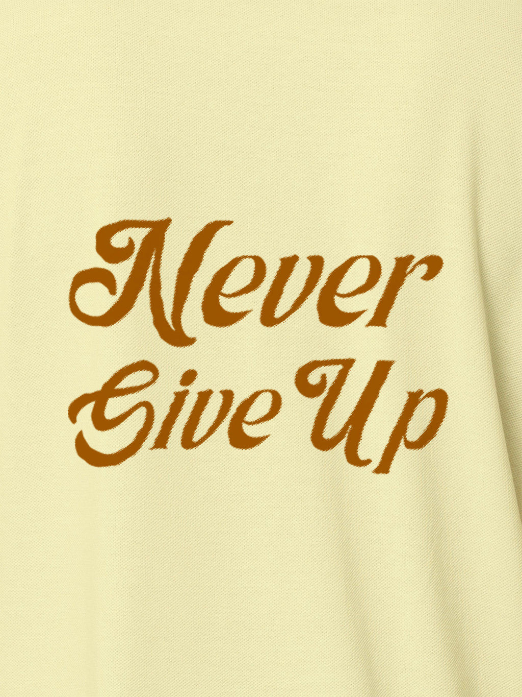 Close up of 'Never Give Up' design on Women's Yellow Polo T-shirt, highlighting intricate details and vibrant print.