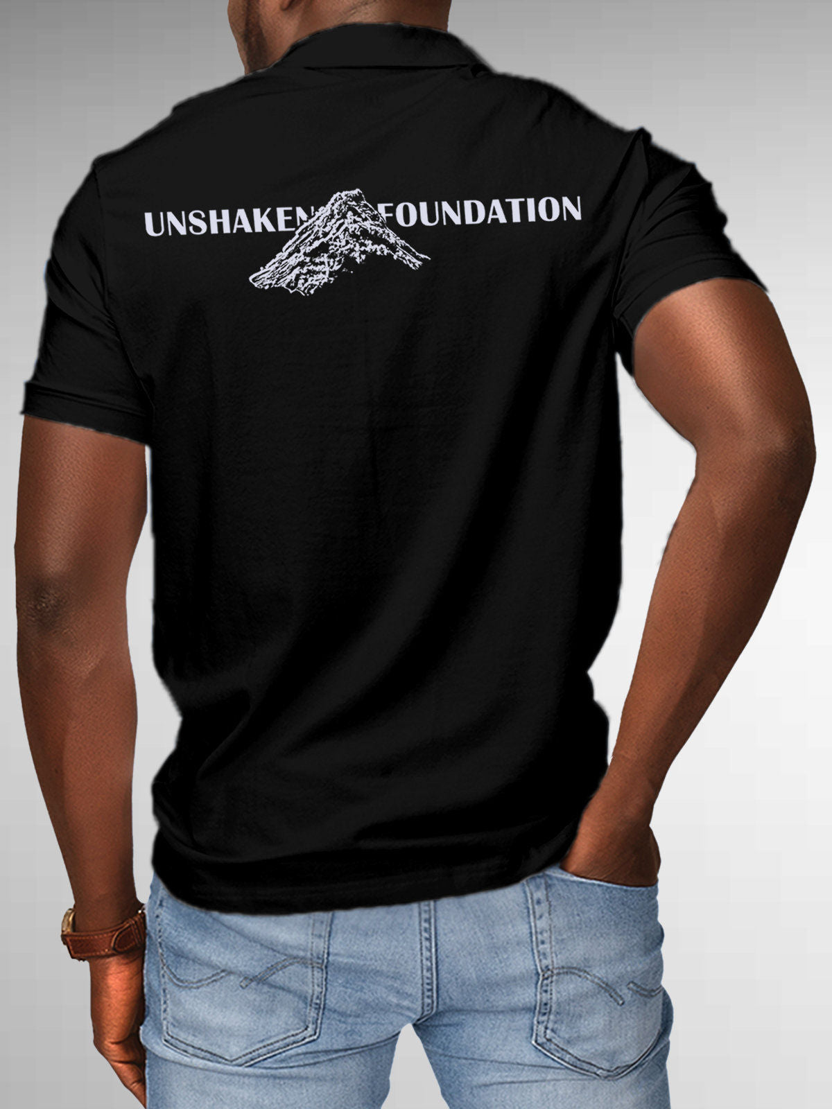 Model wearing Men's Black Polo T-shirt with 'Unshaken Foundation' design, offering effortless style and premium comfort