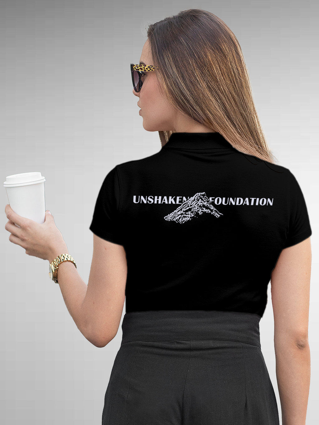 Model wearing Women's Black Polo T-shirt with 'Unshaken Foundation' design, offering effortless style and premium comfort