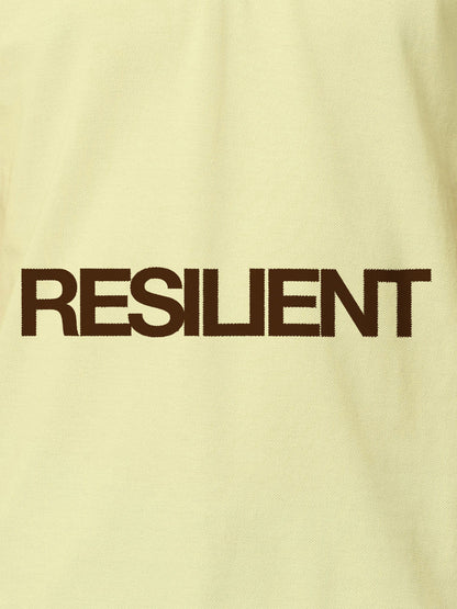 Close up of 'Resilient' design on Women's Yellow Polo T-shirt, highlighting intricate details and vibrant print.