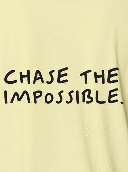 Close up of 'Chase The Impossible' design on Men's Yellow Polo T-shirt, highlighting intricate details and vibrant print.